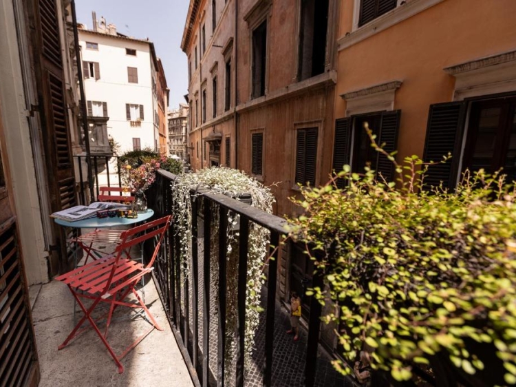 Charming balcony, Red folding chairs, Vibrant greenery, Urban architecture, Sunny ambiance